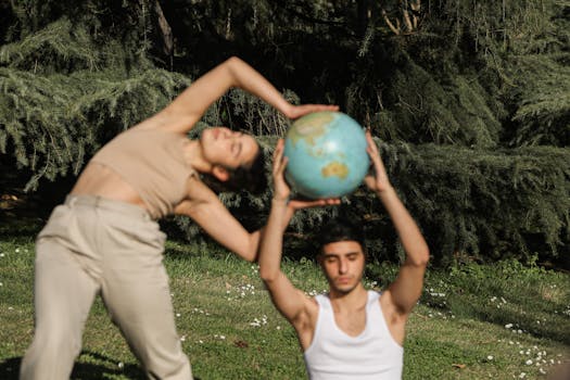 A man and woman in a peaceful yoga pose outdoors, holding a globe.