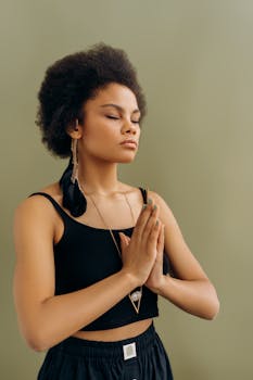 Serene African American woman practicing meditation with hands in prayer pose.